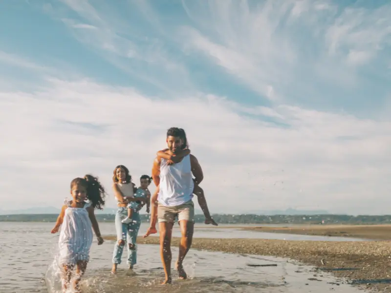 Casal com filhos na praia protegido por seguro de vida